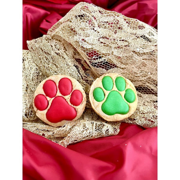 Biscuit artisanal de Noël pour chien en forme de pattes, décoré de glaçage rouge et vert, emballé dans un sachet avec ruban personnalisé Dolci Impronte.